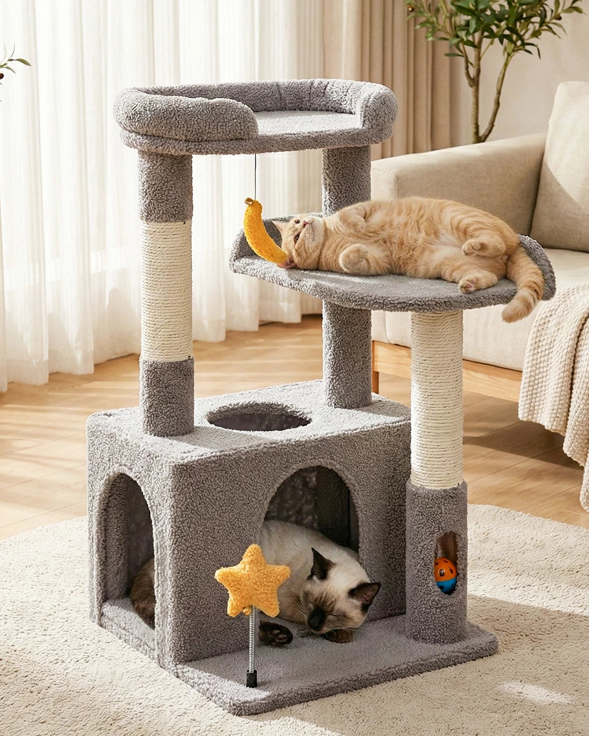 Purrlato Candy Loft 30-inch light grey teddy fleece cat tree tower featuring a Siamese cat sleeping inside the condo and an orange tabby cat playing with the hanging banana toy.